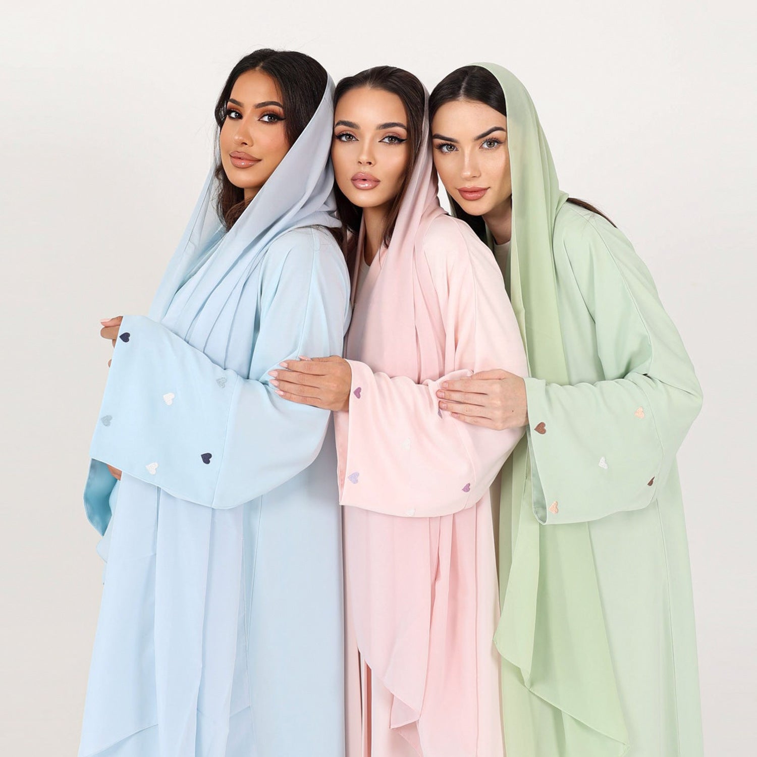 Three women wearing pastel Cardigans & Robes with heart patterns.